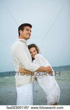 Man and young female companion on beach, embracing View Large Photo Image Stock Photo - Man and young female companion on beach, embracing. Fotosearch
