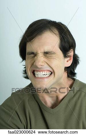 Picture - Man closing eyes and clenching teeth, portrait. Fotosearch
