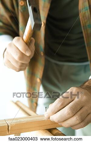 Man hammering nail into piece of wood, close-up of hands View Large Photo Image Stock Image - Man hammering nail into piece of wood, close-up of hands. Fotosearch