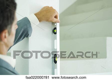 Man holding level against to wall, focus on level View Large Photo Image Stock Image - Man holding level against to wall, focus on level. Fotosearch