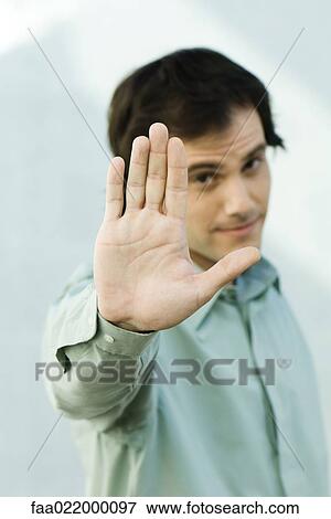 Stock Photo - Man holding up palm to camera, portrait. Fotosearch