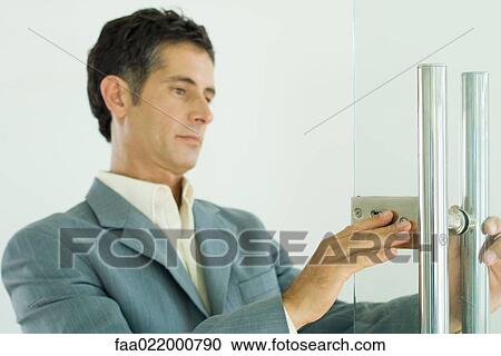 Man in suit inspecting lock on door View Large Photo Image Stock Image - Man in suit inspecting lock on door. Fotosearch