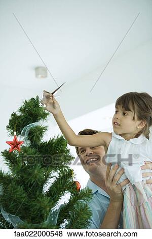 Man lifting girl to place star on top of Christmas tree View Large Photo Image Stock Photo - Man lifting girl to place star on top of Christmas tree. Fotosearch