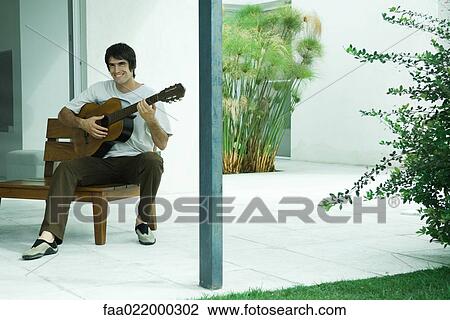 Man playing guitar, smiling, full length portrait View Large Photo Image Stock Image - Man playing guitar, smiling, full length portrait. Fotosearch