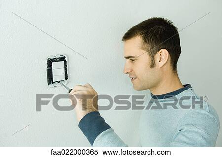 Stock Photography - Man removing light switch cover. Fotosearch