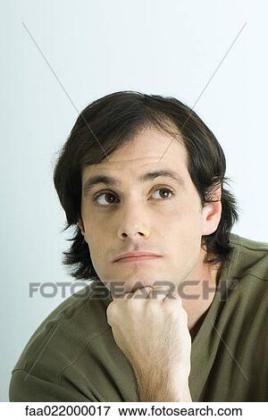 Stock Photo - Man resting chin on hand, looking away, portrait. Fotosearch