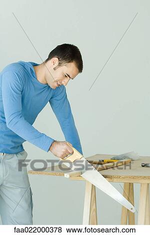 Man sawing wood plank View Large Photo Image Stock Photo - Man sawing wood plank. Fotosearch