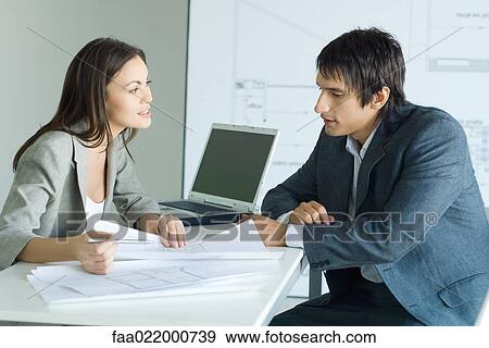 Stock Photo - Man speaking to female architect about blueprints. Fotosearch