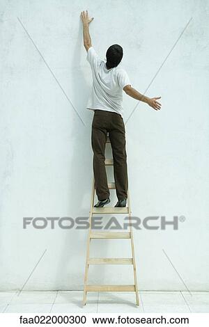 Man standing on ladder, arm raised, rear view View Large Photo Image Stock Image - Man standing on ladder, arm raised, rear view. Fotosearch