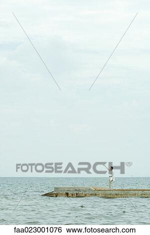 Man standing on pier, looking up, pointing, carrying laptop computer View Large Photo Image Stock Photograph - Man standing on pier, looking up, pointing, carrying laptop computer. Fotosearch