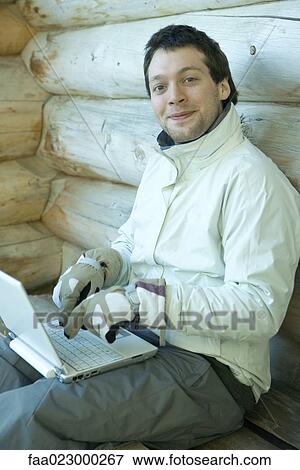 Man using laptop with gloves on, smiling at camera View Large Photo Image Stock Photo - Man using laptop with gloves on, smiling at camera. Fotosearch