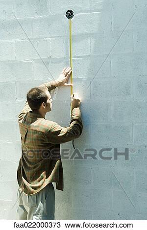 Man using measuring tape on cinder block wall View Large Photo Image Stock Image - Man using measuring tape on cinder block wall. Fotosearch