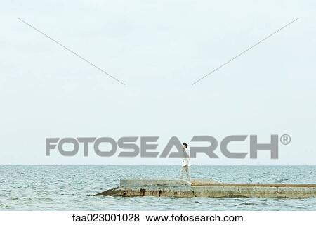 Man walking on pier, carrying laptop computer, full length View Large Photo Image Stock Photo - Man walking on pier, carrying laptop computer, full length. Fotosearch