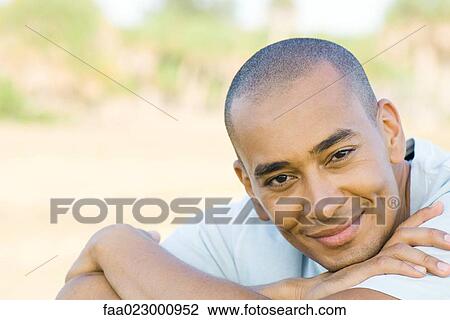 Man with shaved head, smiling at camera, head resting on arms, portrait View Large Photo Image Stock Image - Man with shaved head, smiling at camera, head resting on arms, portrait. Fotosearch