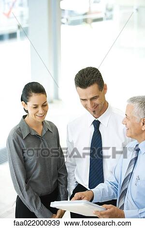 Mature businessman holding file, discussing with associates View Large Photo Image Stock Photo - Mature businessman holding file, discussing with associates. Fotosearch