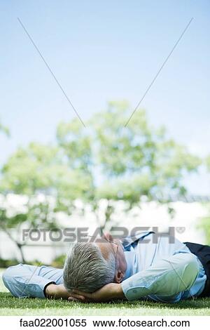 Mature businessman lying on ground outdoors, hands behind head View Large Photo Image Stock Photography - Mature businessman lying on ground outdoors, hands behind head. Fotosearch