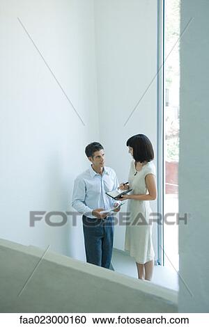 Mature businessman speaking to young female colleague near window, high angle view View Large Photo Image Stock Image - Mature businessman speaking to young female colleague near window, high angle view. Fotosearch