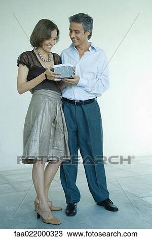Mature couple standing, man handing woman gift, full length portrait View Large Photo Image Stock Image - Mature couple standing, man handing woman gift, full length portrait. Fotosearch