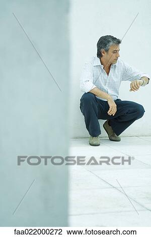 Mature man crouching, checking watch, full length portrait View Large Photo Image Stock Image - Mature man crouching, checking watch, full length portrait. Fotosearch