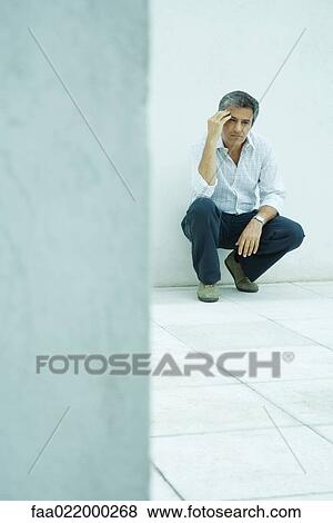 Mature man crouching, holding head, full length portrait View Large Photo Image Stock Photo - Mature man crouching, holding head, full length portrait. Fotosearch