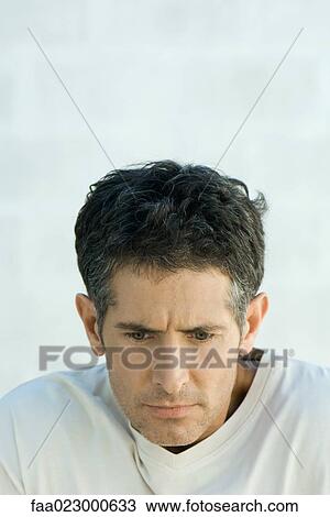 Stock Image - Mature man furrowing brow, looking down, portrait. Fotosearch
