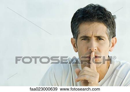 Mature man holding finger over lips, looking at camera, portrait View Large Photo Image Stock Photo - Mature man holding finger over lips, looking at camera, portrait. Fotosearch
