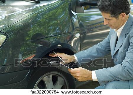 Mature man in suit inspecting car View Large Photo Image Picture - Mature man in suit inspecting car. Fotosearch