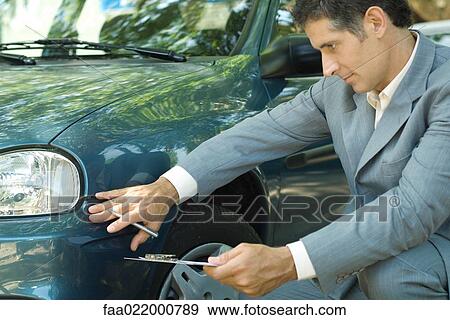 Mature man in suit inspecting car View Large Photo Image Stock Photo - Mature man in suit inspecting car. Fotosearch