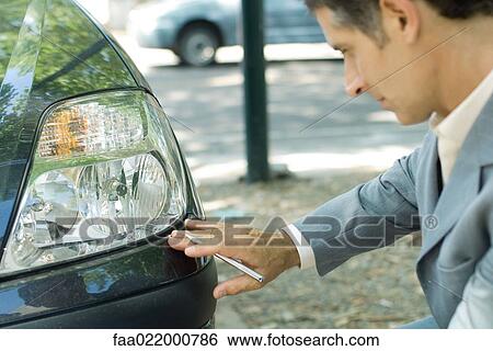 Mature man in suit inspecting car View Large Photo Image Stock Photograph - Mature man in suit inspecting car. Fotosearch
