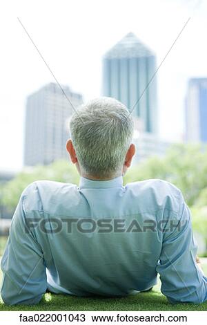 Mature man reclining on ground, looking at urban scene, rear view, close-up View Large Photo Image Stock Image - Mature man reclining on ground, looking at urban scene, rear view, close-up. Fotosearch