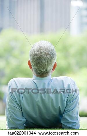 Mature man reclining on ground outdoors, rear view View Large Photo Image Picture - Mature man reclining on ground outdoors, rear view. Fotosearch