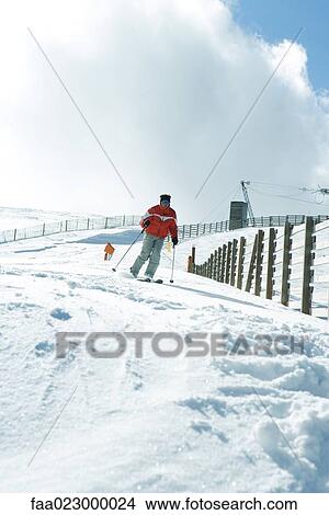 Mature man skiing down ski slope, full length View Large Photo Image Picture - Mature man skiing down ski slope, full length. Fotosearch