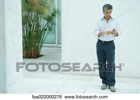 Mature man standing, dialing cell phone, full length portrait View Large Photo Image Stock Photograph - Mature man standing, dialing cell phone, full length portrait. Fotosearch