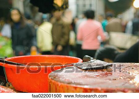 Stock Image - Meat cleaver on chopping block in market, close-up. Fotosearch