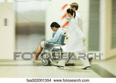 Picture - Medical staff pushing man in wheelchair, blurred motion. Fotosearch