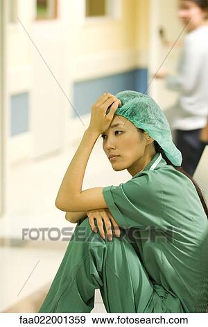 Medical worker sitting on floor in hospital corridor, holding head, looking away View Large Photo Image Stock Photo - Medical worker sitting on floor in hospital corridor, holding head, looking away. Fotosearch