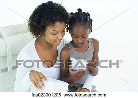 Mother and daughter looking at present, girl sitting on woman's lap View Large Photo Image Stock Photography - Mother and daughter looking at present, girl sitting on woman's lap. Fotosearch