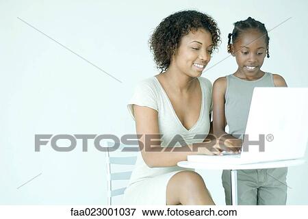 Mother and daughter using laptop computer together, smiling, looking down View Large Photo Image Stock Photo - Mother and daughter using laptop computer together, smiling, looking down. Fotosearch