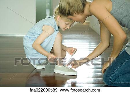 Mother helping little girl tie shoe laces View Large Photo Image Stock Photo - Mother helping little girl tie shoe laces. Fotosearch