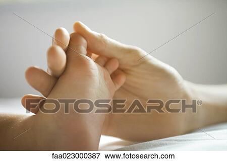 Stock Photo - Mother's hand holding baby's foot, close-up. Fotosearch