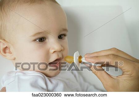 Stock Image - Mother's hand holding up pacifier for baby. Fotosearch