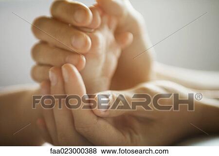 Stock Photo - Mother's hands holding baby's foot, close-up. Fotosearch