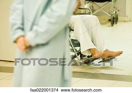 Picture - Patient sitting in wheel chair, cropped view, adult with clasped hands in foreground. Fotosearch