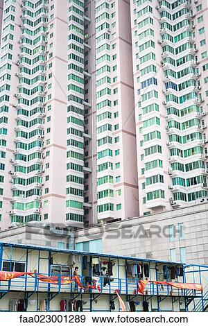 Person hanging clothes out to dry on terrace of low apartment building, skyscraper towering in background View Large Photo Image Stock Photo - Person hanging clothes out to dry on terrace of low apartment building, skyscraper towering in background. Fotosearch