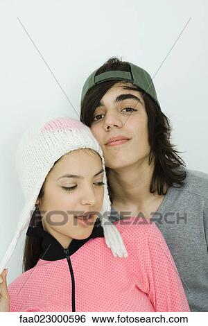 Stock Photograph - Portrait of young couple, both wearing hats, male smiling at camera, female looking away. Fotosearch