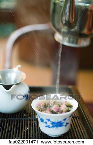 Stock Image - Pouring hot water into flower and tea mixture. Fotosearch