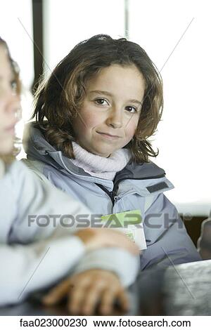 Stock Image - Preteen girl in winter clothes, looking at camera. Fotosearch