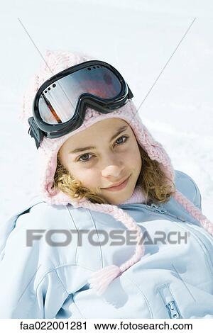 Stock Image - Preteen girl wearing ski gear, smiling at camera, portrait. Fotosearch