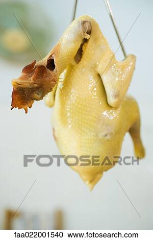 Stock Image - Raw skinned chicken hanging from hook. Fotosearch