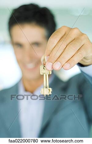 Real estate agent holding up keys, focus on keys in foreground, close-up View Large Photo Image Stock Image - Real estate agent holding up keys, focus on keys in foreground, close-up. Fotosearch
